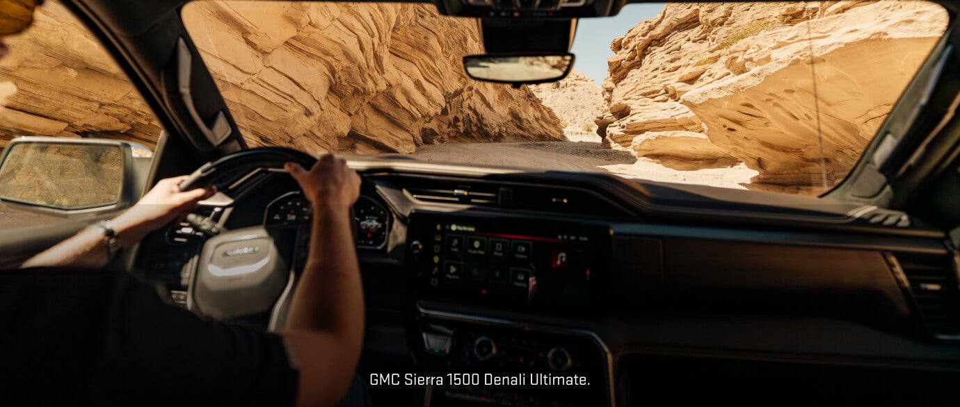 Driver-perspective interior view of an 2026 GMC Sierra 1500 Denali Ultimate navigating a winding dirt trail.