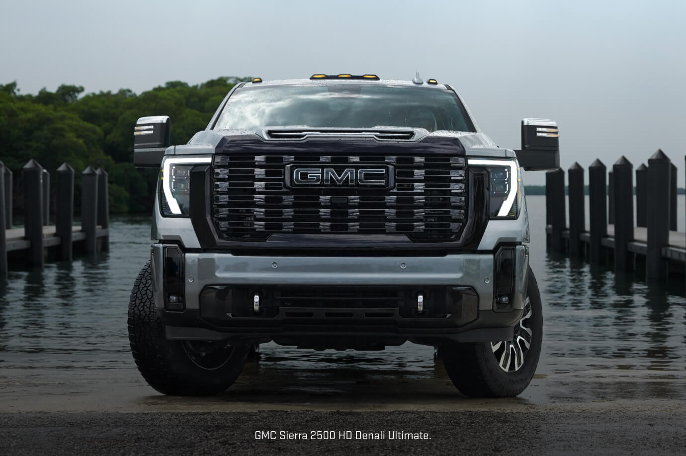 Front view of a Gray 2026 GMC Sierra 2500 HD Denali Ultimate parked on a concrete boat ramp.